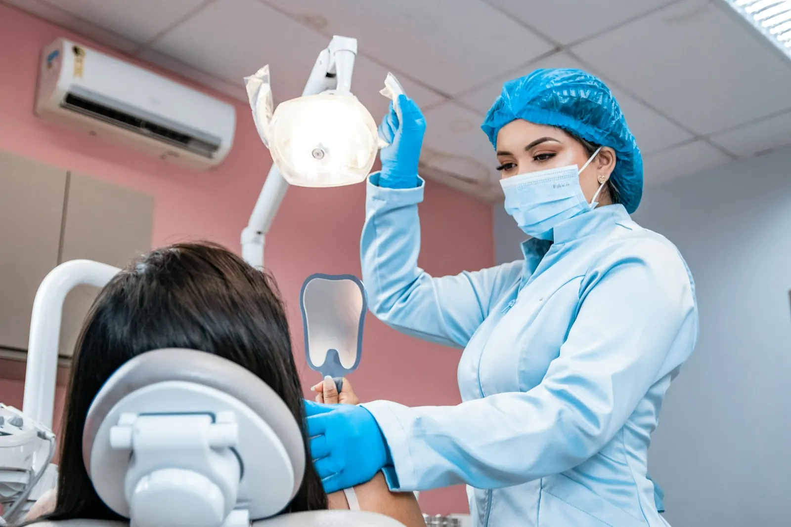 Dentista atendendo uma paciente sentada na cadeira do consultório